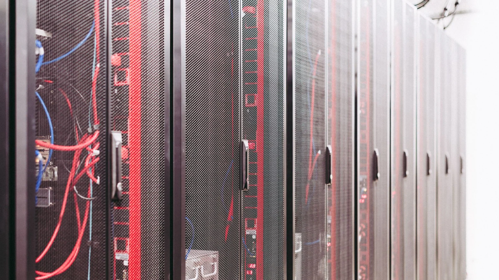 Rows of server racks with red network cables inside a data center aisle