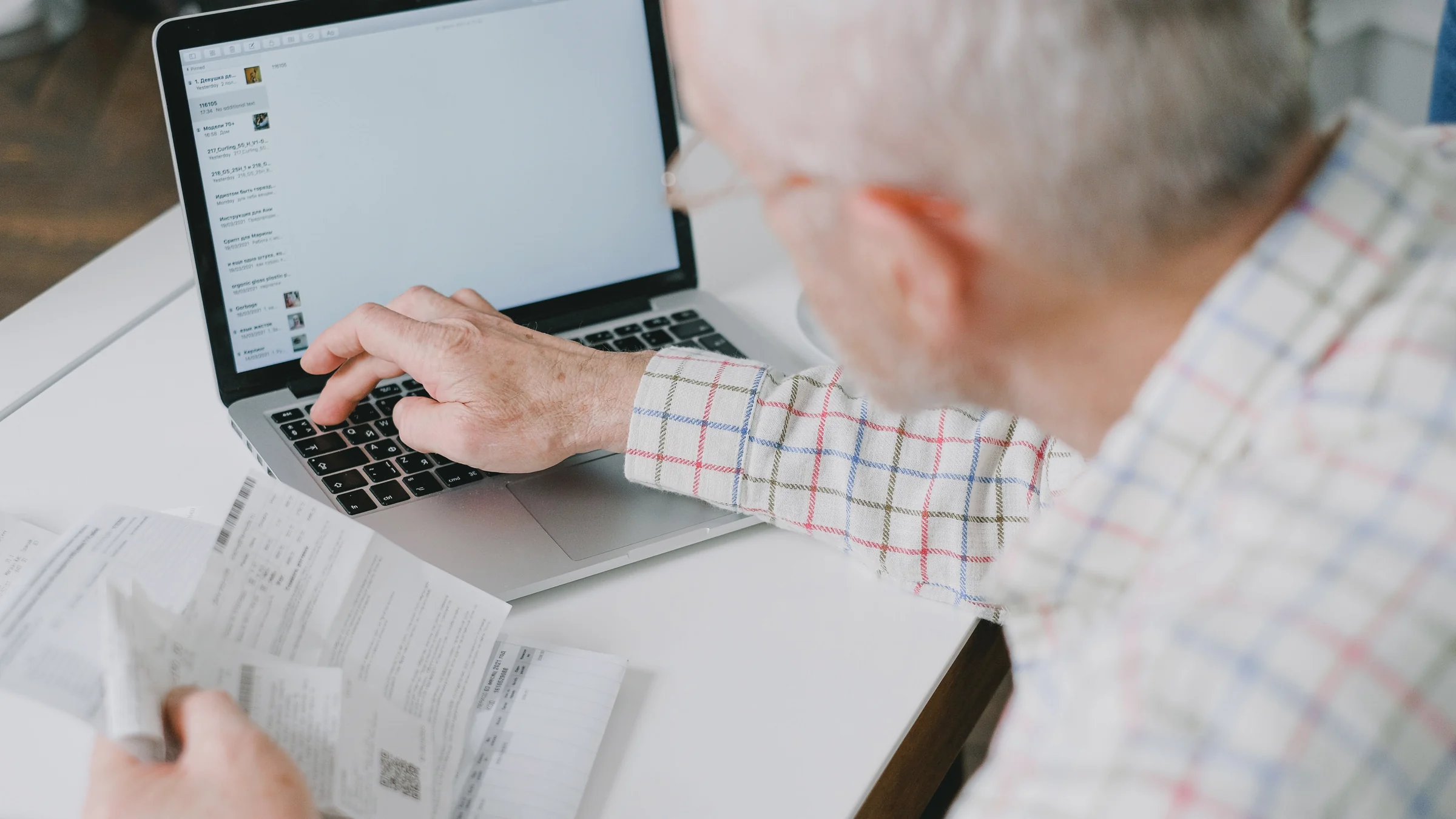 A person compares paper documents with a laptop screen while checking whether an AI search answer can be trusted