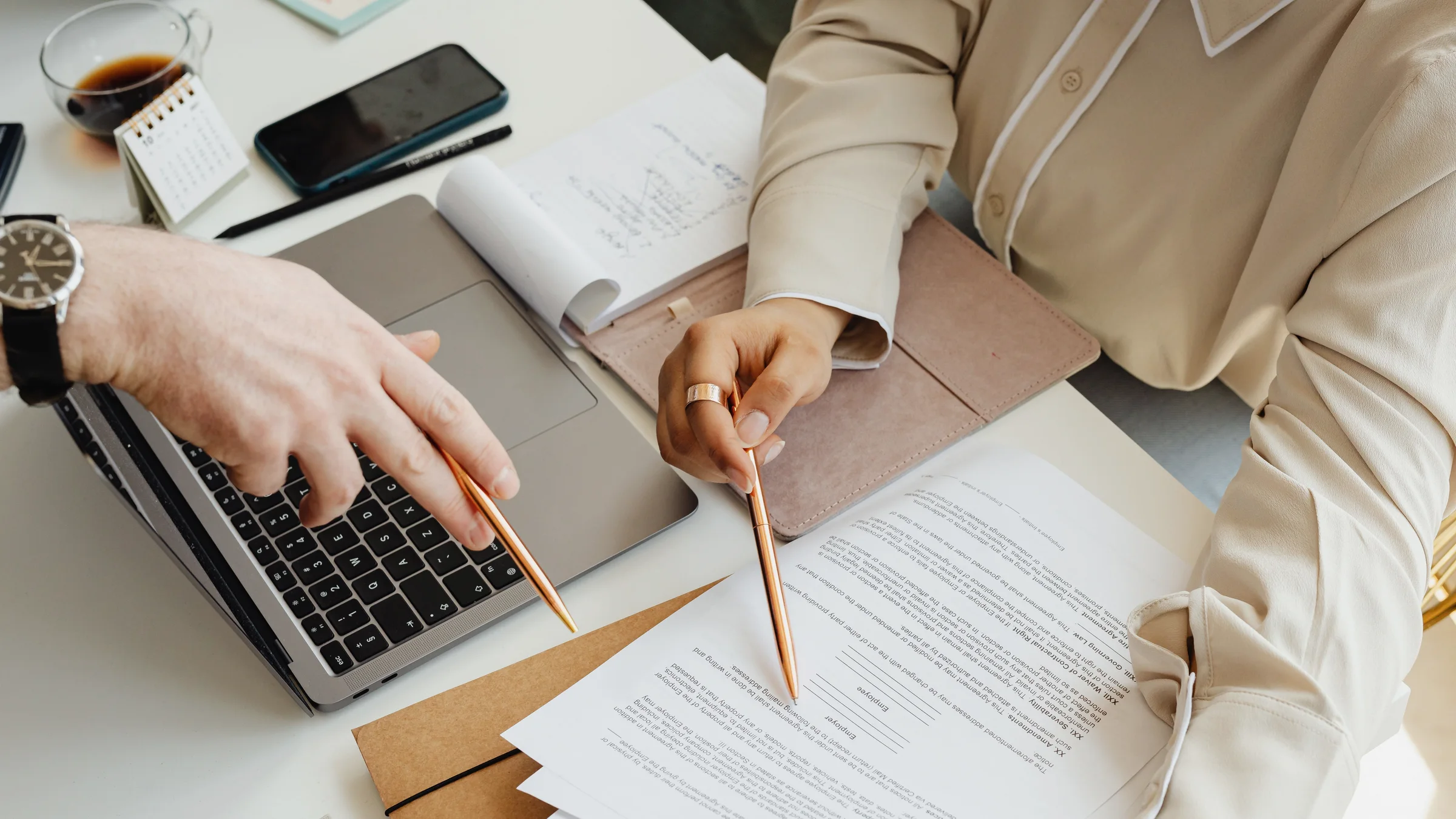 Two people reviewing printed documents beside a laptop, used to show how AI-generated reports can move hidden review work to coworkers