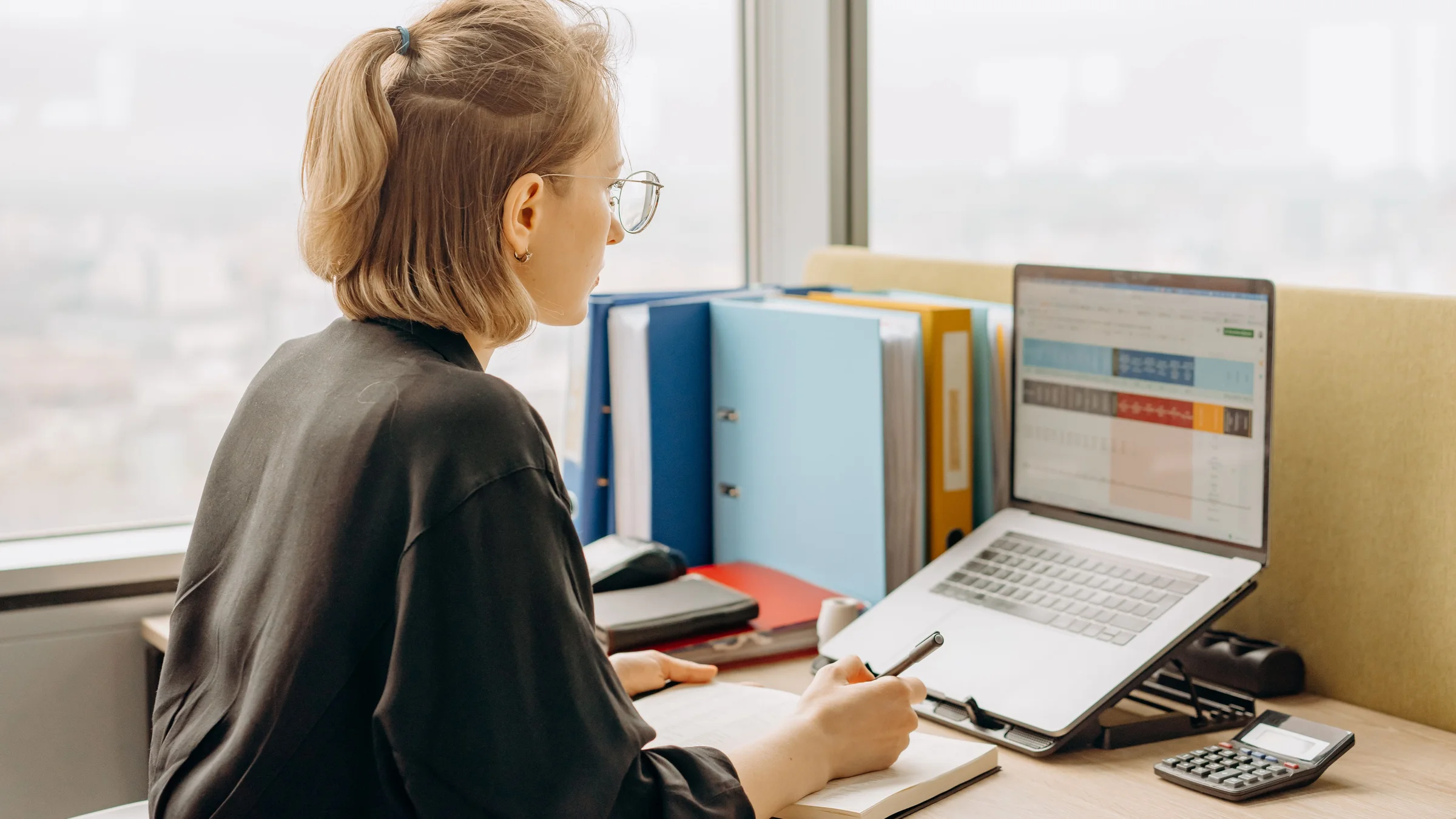 A person working with a spreadsheet on a laptop beside folders and a calculator, used for an Excel AI workflow guide
