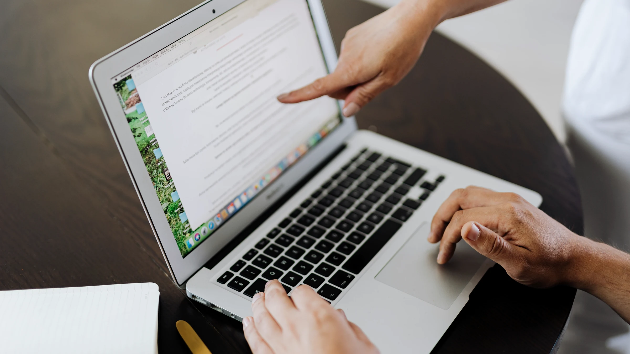 Two people review a laptop document together, turning a work instruction into a repeatable Markdown workflow